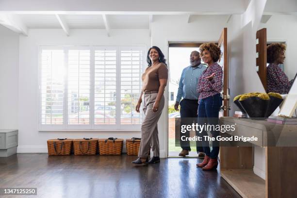 full length of smiling female real estate agent showing home to mature couple - couple real life stockfoto's en -beelden