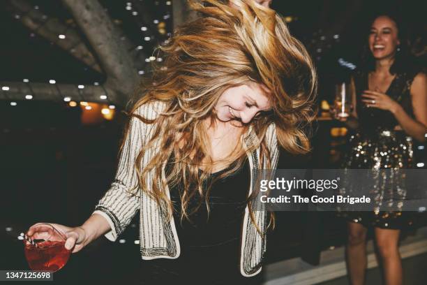happy young woman tossing hair while dancing at party - sacudir el pelo fotografías e imágenes de stock