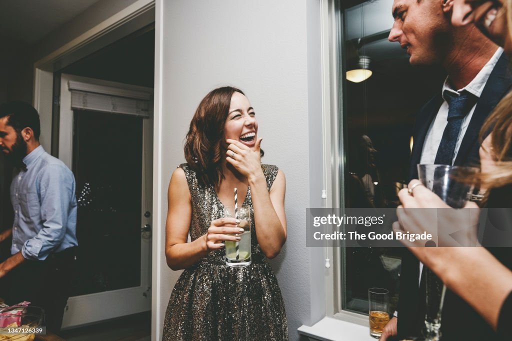 Cheerful woman looking at male friend while talking at party