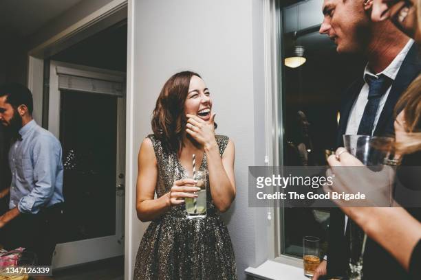 cheerful woman looking at male friend while talking at party - party dress stock-fotos und bilder