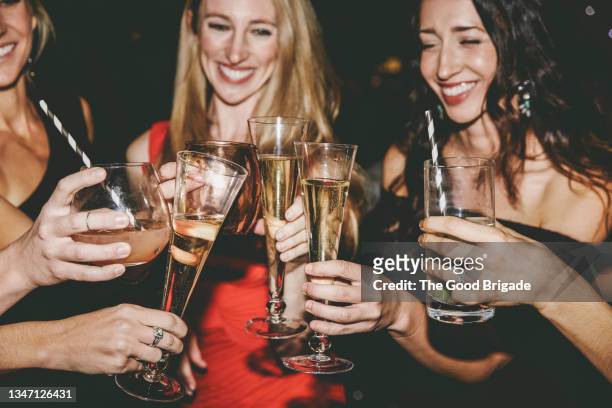 happy women making toast while celebrating at party - woman holding champagne stock-fotos und bilder