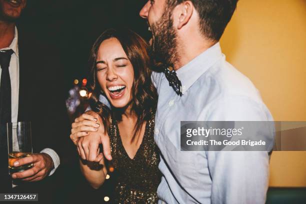 woman laughing with male friends while enjoying at party - putting arm around shoulder stock pictures, royalty-free photos & images