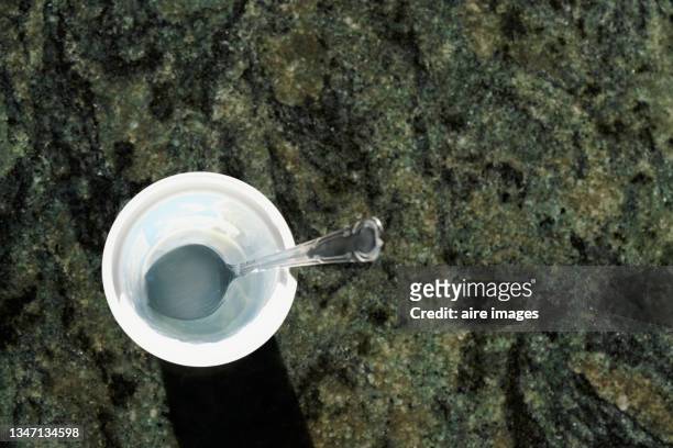 empty plastic cup with teaspoon on rock surface - einmachglas leer stock-fotos und bilder