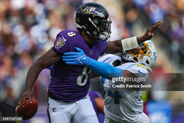 Quarterback Lamar Jackson of the Baltimore Ravens stiff arms outside linebacker Kyzir White of the Los Angeles Chargers during the first half at M&T...