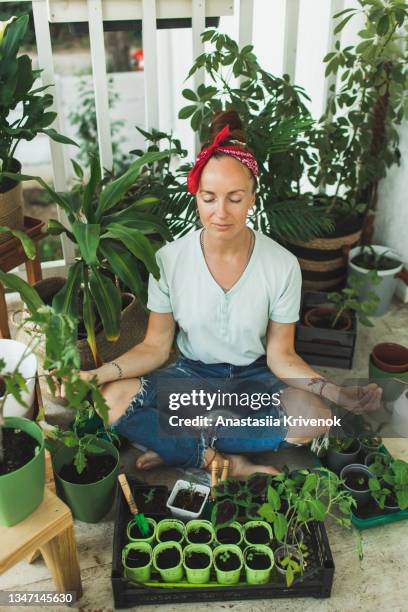 young caucasian woman repotting plants and relaxing on the home terrace. - militant photos et images de collection