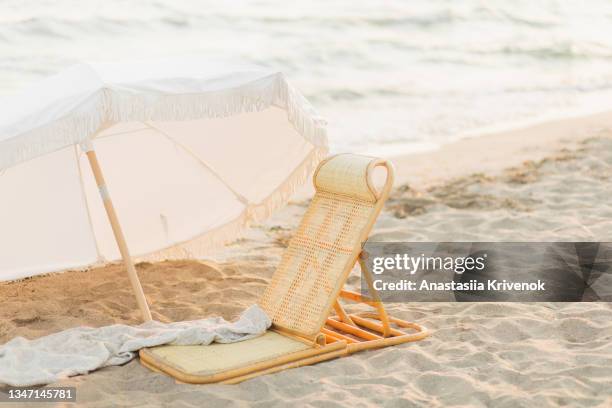 decorative white parasol and bamboo deck chair against ocean. - chaise longue stock pictures, royalty-free photos & images