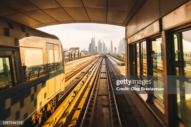 driverless automatic metro train moving on station in dubai at sunset - emirates towers stockfoto's en -beelden