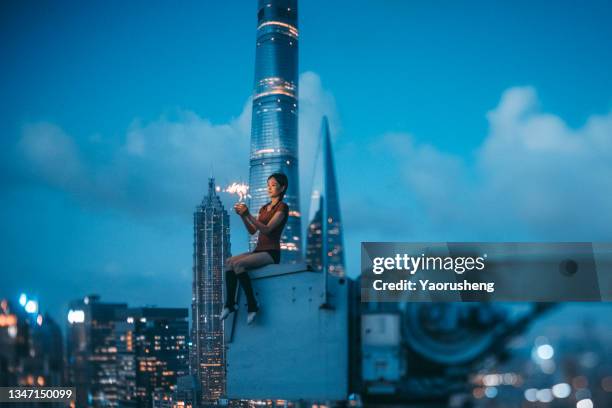 happy night--one woman  holding sparkelers on the building rooftop,against modern city building - shanghai imagens e fotografias de stock