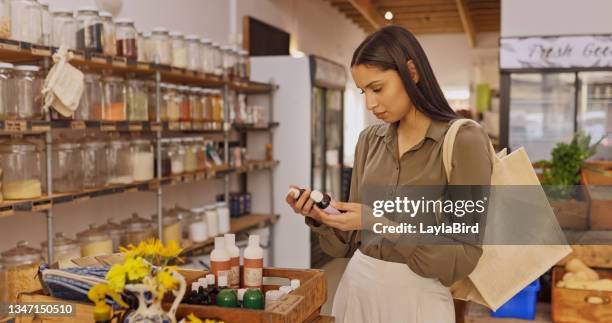 photo d’une jeune femme lisant l’étiquette d’une bouteille dans une épicerie - regard beauté femme photos et images de collection