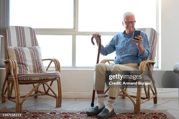 shot of a senior man using a smartphone while relaxing at home - stick shift stock pictures, royalty-free photos & images