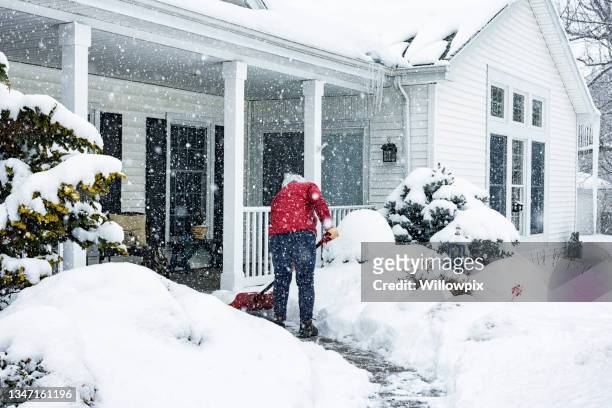red jacket woman push shoveling winter blizzard snow - deep snow stockfoto's en -beelden