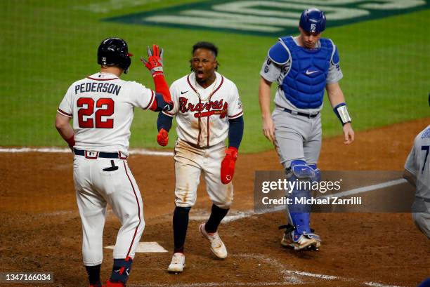 Ozzie Albies of the Atlanta Braves is congratulated by Joc Pederson after he slide past Will Smith to score in the eighth inning of Game Two of the...