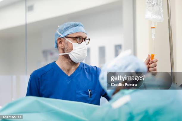 medizinische fachkraft, die iv. tropf im krankenhaus untersucht - anesthesiologist stock-fotos und bilder
