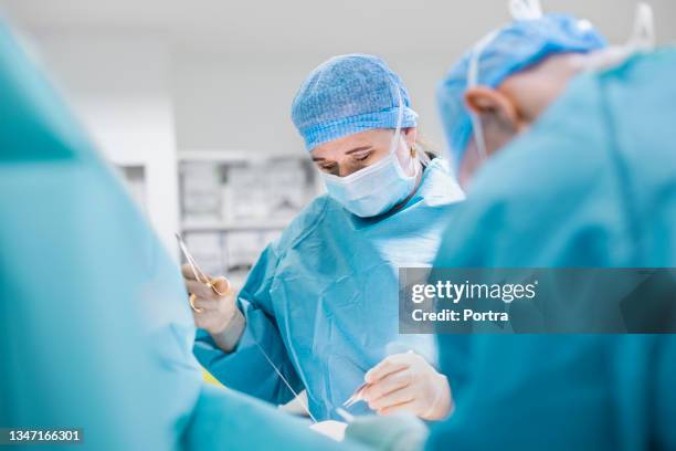 female surgeon doing stitches in operating room - hecht stockfoto's en -beelden