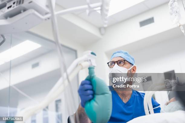 anesthetist squeezing ambu bag in operating room - anaesthetist stock pictures, royalty-free photos & images