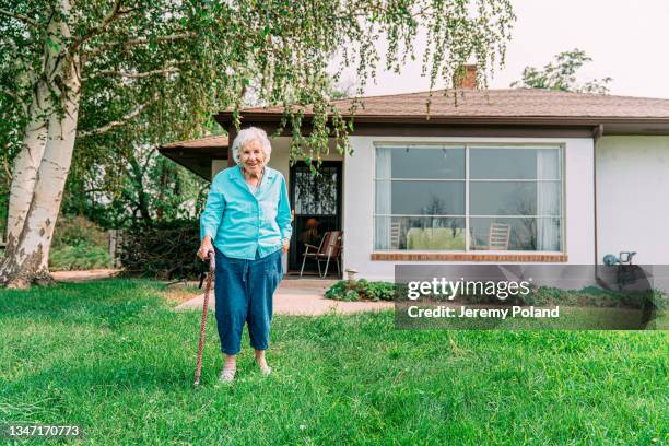 sweet elderly 100-year-old senior woman standing outdoors in front of her home in the summer - 90 year old stockfoto's en -beelden