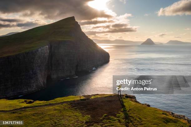 a man on a cliff near sorvagsvatn or leitisvatn lake. at sunrise faroe islands. - 38 north stock-fotos und bilder