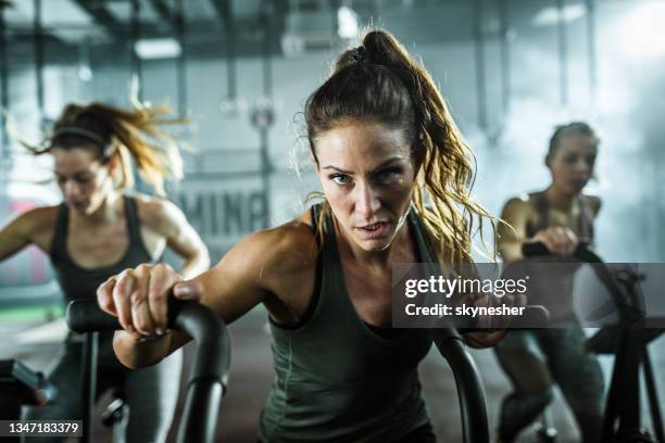 femme athlétique déterminée pendant le cours d’exercice à vélo dans un gymnase. - cours de spinning photos et images de collection