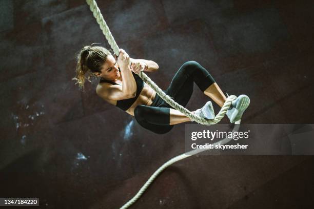 above view of athletic woman moving up the rope in a gym. - clambering imagens e fotografias de stock