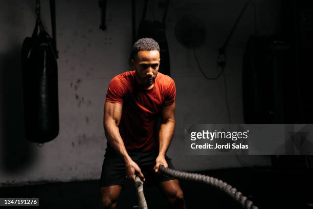 man with battle ropes in a gym - intensidad del color fotografías e imágenes de stock
