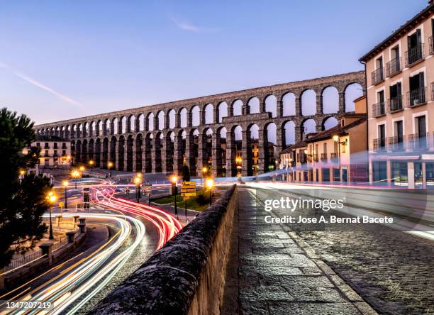 view of the acueducto romano (roman aqueduct), view of the aqueduct at dawn with the lights and wakes of the cars in motion. - segovia stock-fotos und bilder