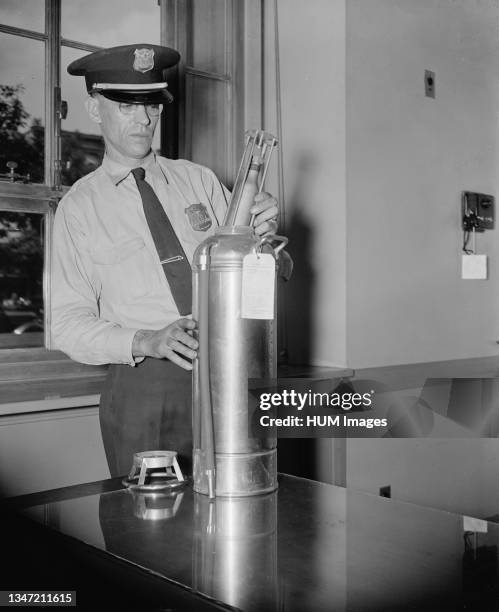 An officer in the Justice Department Guards, examines a new type of fire extinguisher cartridge, the cartridge is filled with carbon dioxide gas...