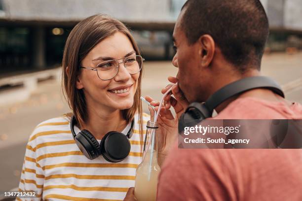 couple drinking soda together - rietje stockfoto's en -beelden