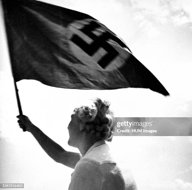 Woman waving Nazi flag circa late 1930s or early 1940s.