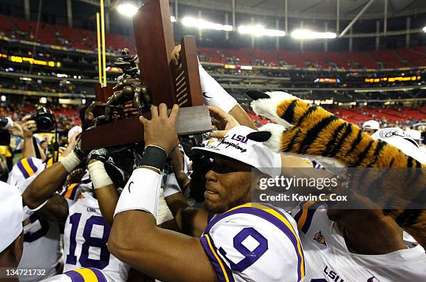 Jordan Jefferson of the LSU Tigers helps carry the 2011 SEC Championship trophy after their 42-10 win over the Georgia Bulldogs at Georgia Dome on...