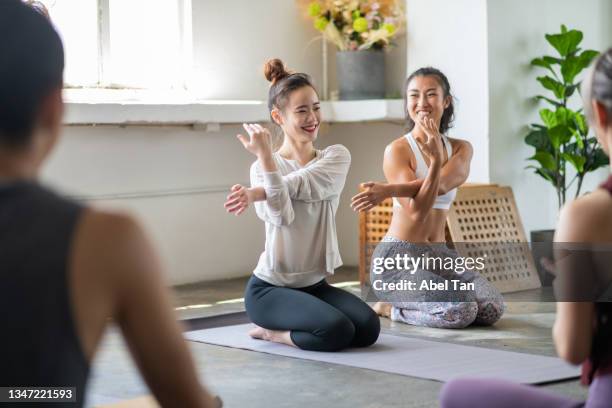 joven asiática en clase de yoga con instructor de yoga en estudio de yoga foto de archivo - crecimiento estirón fotografías e imágenes de stock