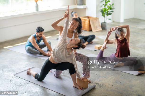 young asian female stretching in yoga class with yoga instructor in yoga studio stock photo - yoga studio stock pictures, royalty-free photos & images