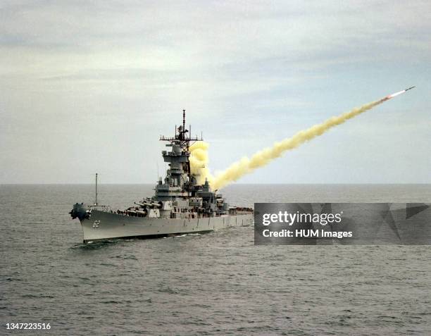 An aerial port bow view of the battleship USS NEW JERSEY launching an RGM-84 Harpoon missile on the Pacific Missile Test Center Range..