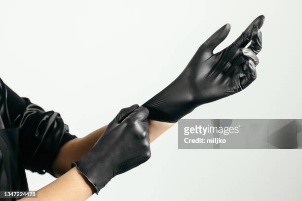 putting on latex protective glove - black glove stock pictures, royalty-free photos & images