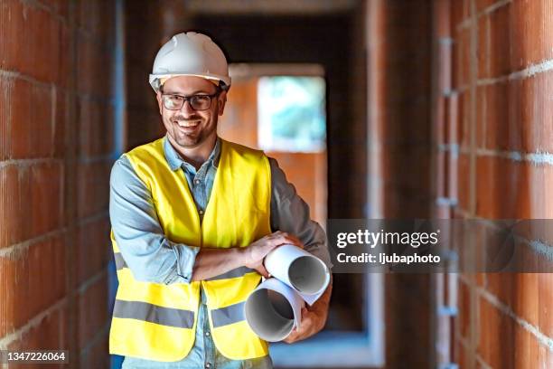 architect holding blueprints on construction site - architekt helm plan stock pictures, royalty-free photos & images