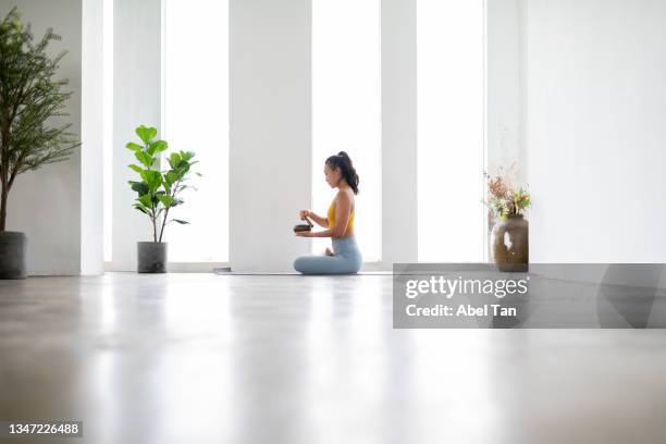 young asian female chinese adult solo yoga pose in brightly lit yoga studio stock photo - young man asian silhouette stock pictures, royalty-free photos & images