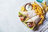 Chicken gyros with vegetables, french fries and tzatziki sauce on plate. Greek food concept.