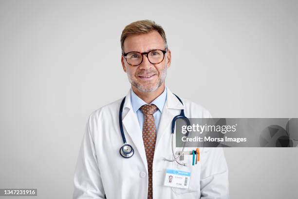 confident male doctor against white background - arzt stock-fotos und bilder