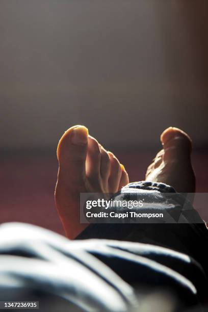 close up of white caucasian naked feet and toes indoors - legs crossed at ankle stock-fotos und bilder