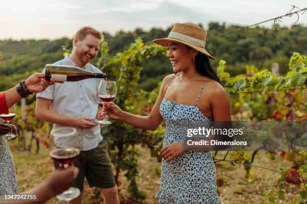 glückliche weintouristen, die wein im weinberg probieren - weingut stock-fotos und bilder