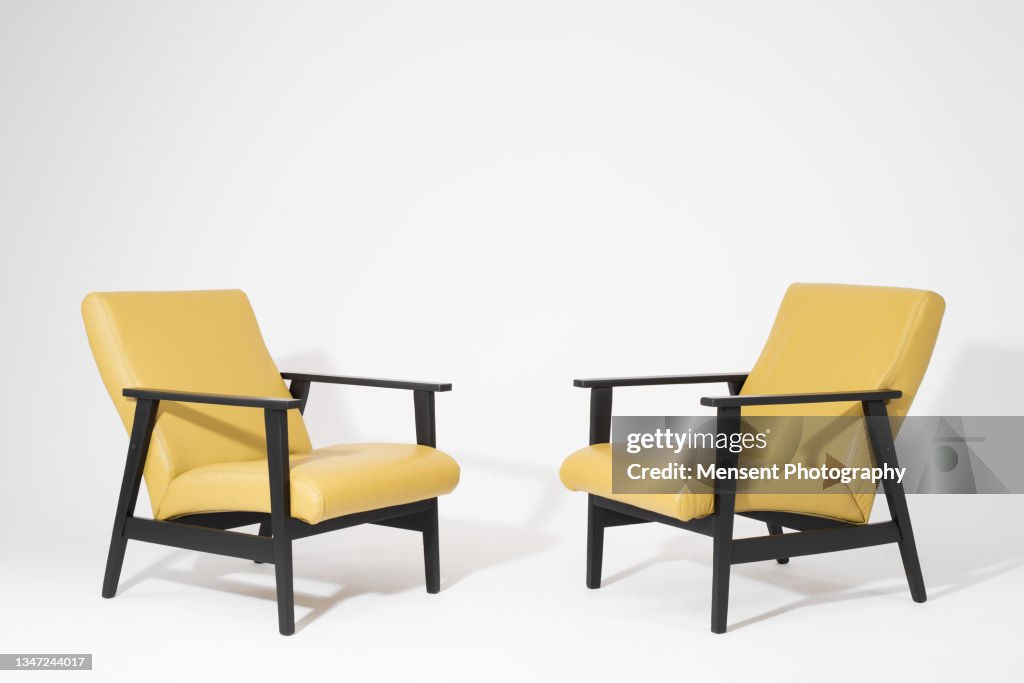 Two modern yellow armchairs isolated on a white background
