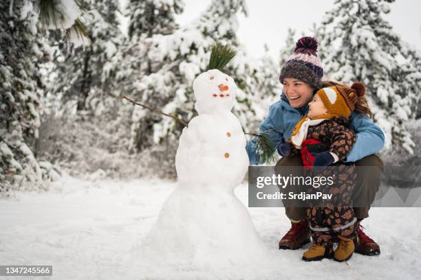 curieux garçon toodler observant sa mère alors qu’elle fabriquait un bonhomme de neige - snowman photos et images de collection