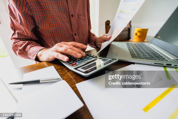 hombre mayor revisando facturas en casa - bills fotografías e imágenes de stock