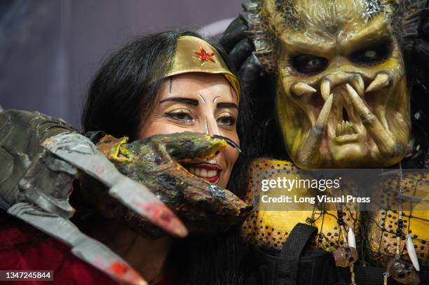 Cosplayer with a Predator costume poses for a photo with a women cosplaying Wonder Woman during the first day of the SOFA 2021, a fair aimed to the...