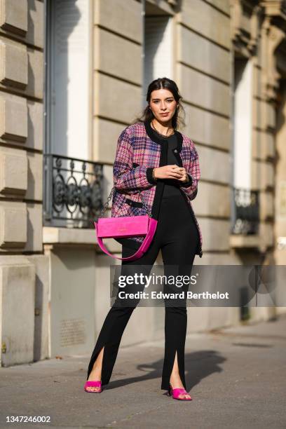 Katie Giorgadze wears front slit black flared leggings from Bershka, a black halter neck bodysuit from Zara, an oversized pink tweed jacket with...