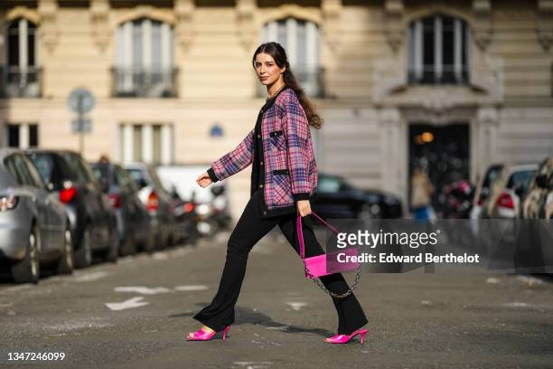 Katie Giorgadze wears front slit black flared leggings from Bershka, a black halter neck bodysuit from Zara, an oversized pink tweed jacket with...