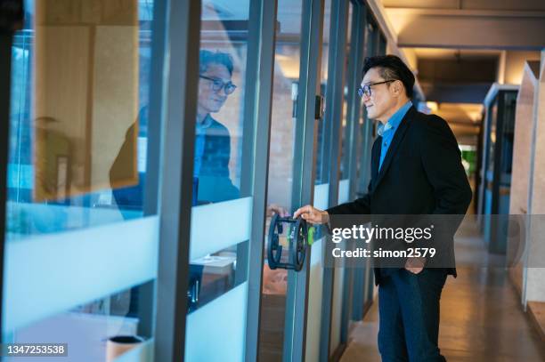an asian businessman with report at doorway in office - office door stock pictures, royalty-free photos & images