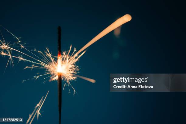 burning sparkler with many beautiful sparks on blue background. concept of new year or birthday celebration. copy space for your design - sparkler firework stock-fotos und bilder