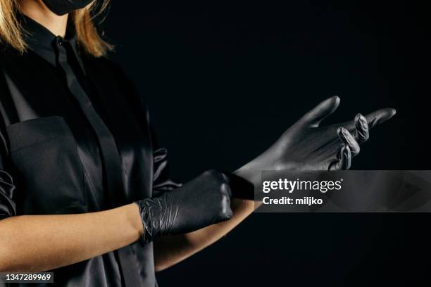 putting on latex protective glove - black glove stock pictures, royalty-free photos & images