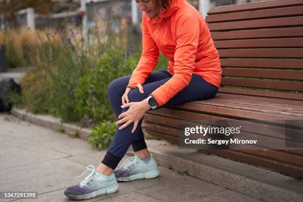 woman  holds on to a sore knee after jogging - female muscular calves fotografías e imágenes de stock