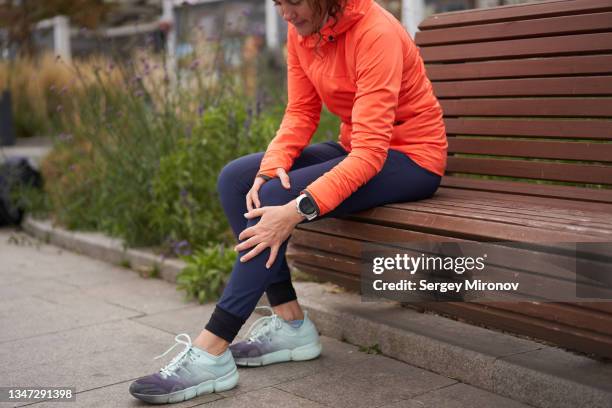 woman holds on to a sore knee after jogging - knee pain stock pictures, royalty-free photos & images